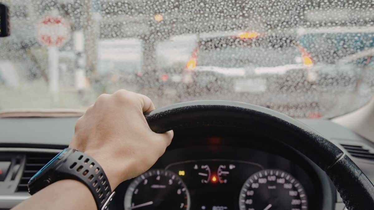 Driving in the rain with a wet windshield and hands on the wheel